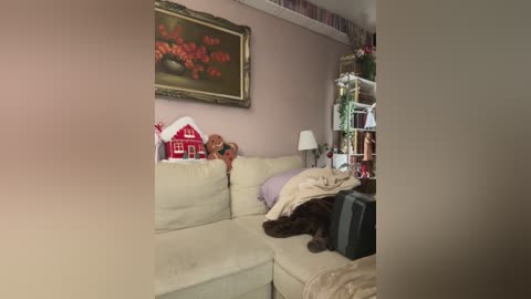 Media: A video of a cozy living room with a beige sectional sofa, a framed painting of flowers, a red barn decoration, a lamp, and a brown dog resting.