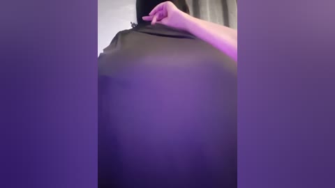 Media: Video of a person wearing a black shirt, slightly lifting the fabric to reveal a small part of their breast, with a purple background.