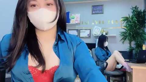 Media: Video of two women in a modern office: one with long dark hair and a red lace bra, the other with short black hair and a mask, seated at desks.