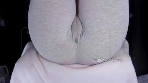 Media: Video of a woman's bare buttocks, showing a dimpled, light skin tone. She is seated on a white cloth, with a black background.