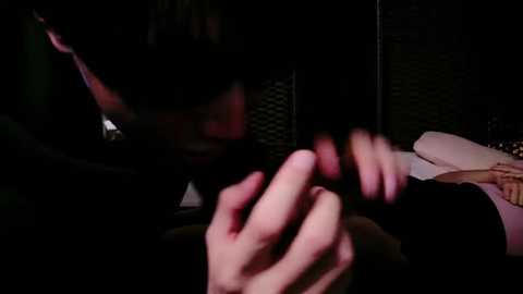 Media: A dimly lit video shows a man with short, dark hair and a serious expression, holding a cigarette close to his face, with a faintly visible woman in the background.