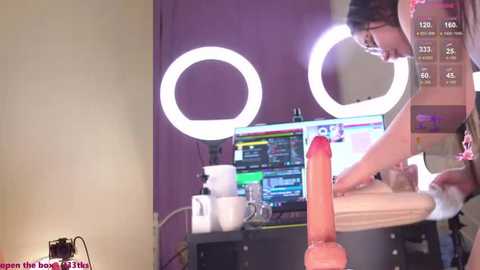 Media: A video shows a woman with fair skin, glasses, and dark hair, using a large dildo, with a digital display in the background.