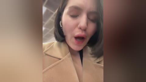 Media: A blurred video of a young woman with short, straight, dark hair, wearing headphones, appears to be in a state of surprise or shock, captured from an upward angle.