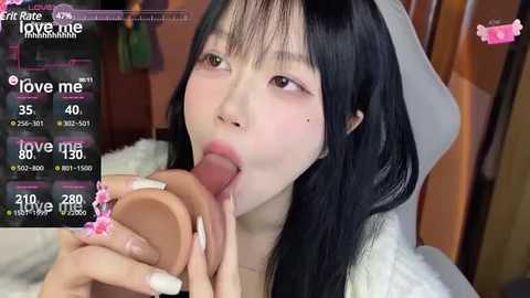 Media: A video of an Asian woman with long black hair, wearing a white robe, performing oral sex on a realistic, flesh-colored dildo. The background features a wooden wall and a pink heart.