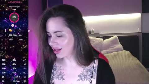 Media: Video of a young woman with long brown hair, wearing a black and white floral top, smiling, in a dimly lit room with a starry background.