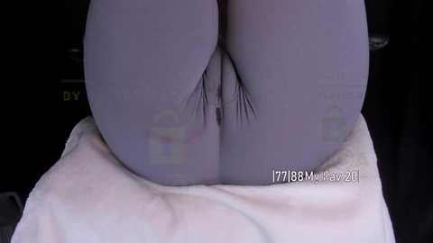 Media: Video of a close-up of a person's buttocks and genitals, wearing light purple leggings, seated on a white towel, with a watermark reading \"1778M/NEV20\" in the bottom right.