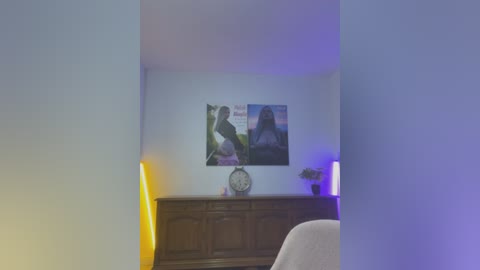 Media: A video of a dimly lit room with a white wall, a wooden dresser, two posters, a clock, and a lamp emitting purple light.