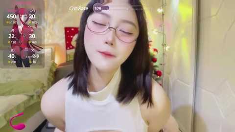 Media: Video of a young Asian woman with fair skin, straight black hair, and glasses, wearing a white tank top, smiling in a cozy, softly lit bedroom.