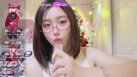 Media: A video of an East Asian woman with straight black hair, wearing glasses and a white tank top, holding a water bottle in a room with festive decorations.