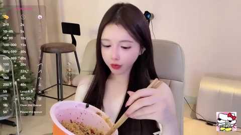 Media: A video of an Asian woman with long black hair, wearing a black top, mixing brown batter in a pink bowl. Background includes a white chair and a Christmas tree, with a live stream overlay.