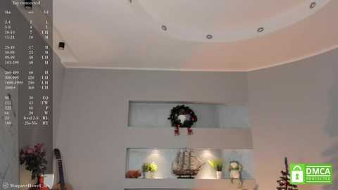 Media: Video of a modern living room with minimalist decor. Grey walls, recessed shelves, and a small Christmas wreath. The \"DMCA\" logo is visible in the bottom right corner.