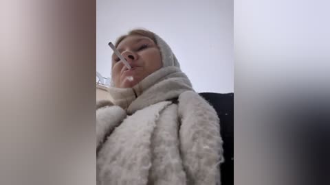 Media: Video of a blonde woman wearing a beige blanket, a nose clip, and a snorkel, with a blurred background.