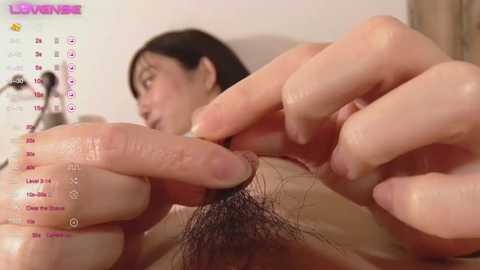 Media: A close-up video of a woman's hands grooming her pubic hair, with a blurred background showing her face and a calendar displaying the date \"11/22\".