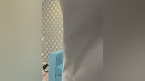 Media: Video of a man's bare, muscular buttocks in a room with a light blue chair, white patterned wallpaper, and scattered clothing on the floor.