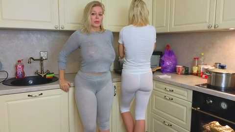 Media: Video of two older women in matching light blue pajamas, one with a large chest, the other with a curvy figure, standing in a modern kitchen.