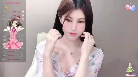 Media: Video of a fair-skinned, East Asian woman with long dark hair, wearing a white, floral-patterned nightgown, adjusting her hair. Background shows a video game screen with a character.