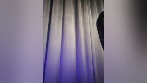 Media: Video of a stage curtain with a gradient from light gray at the top to dark gray at the bottom, slightly illuminated from behind, revealing subtle texture.