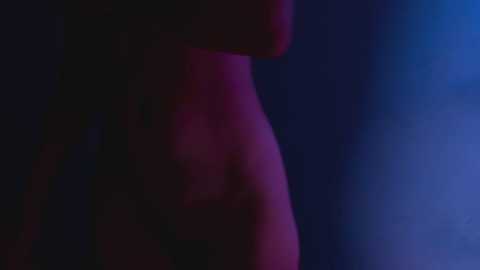 Media: Video with a digital filter, featuring a partially visible person's back, illuminated by a purple and blue light. The image has a soft, ethereal quality, with indistinct details and a dreamy atmosphere.