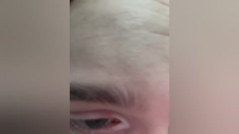 Media: Video of a person's partially obscured face, focusing on the eye, which is closed with a slight redness around the corner. The skin tone is light, and the background is a neutral, blurry beige.