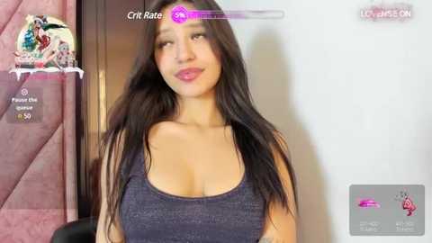 Media: Video of an attractive woman with long black hair, fair skin, and wearing a low-cut, dark gray tank top, posing indoors.