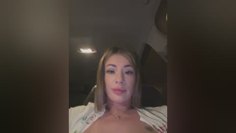 Media: A video of a young, light-skinned woman with straight blonde hair, wearing a white blouse, sitting in the back seat of a car.