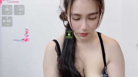 Media: Video of a young Asian woman with long black hair, wearing a black lace bra, against a white background.