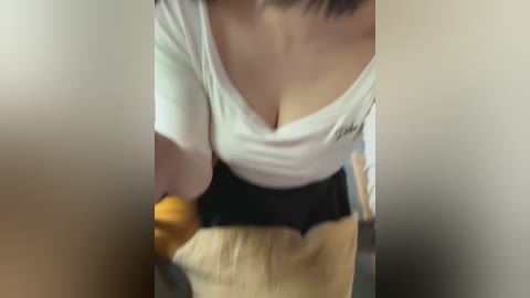 Media: Video of a woman with fair skin and medium breasts wearing a white off-shoulder top and a black skirt. She holds an orange in her left hand. The background is blurred.