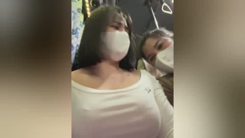 Media: Video of two women on a subway train, one with long black hair, wearing a white mask, and the other with short grey hair.