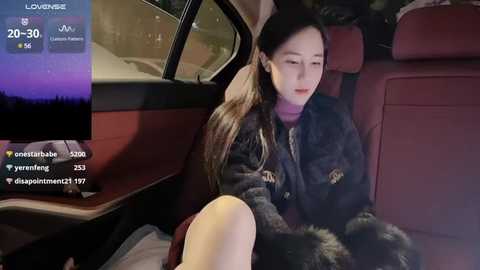 Media: Video of a young woman in a dark coat, sitting in a car at night, looking out the window with a contemplative expression.