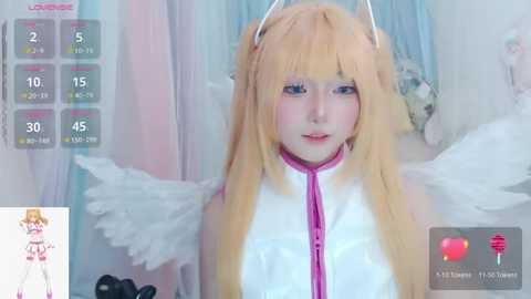 Media: Video of a young woman with long, blonde hair and white angel wings, wearing a white and pink outfit. Background features pastel-colored curtains and a virtual chatroom interface.