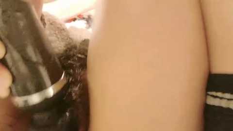 Media: A close-up video of a woman's bare thigh, with a black, furry dog licking her skin. The background is out of focus, showing a tiled bathroom.