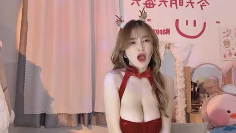 Media: A video of an East Asian woman with long, wavy hair, wearing a red, revealing bunny costume with a bow, in a cozy bedroom with plush toys and posters.