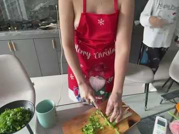 Media: A video of a fair-skinned woman in a red apron with \"Happy Christmas\" and Santa Claus, chopping green vegetables on a kitchen counter.