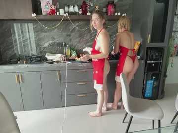 Media: Video of two middle-aged women in red aprons cooking in a modern kitchen with gray cabinets, marble backsplash, and stainless steel appliances.