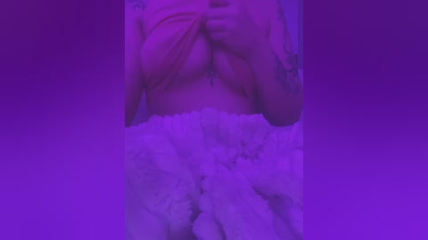 Media: A video of a nude woman with fair skin, medium-sized breasts, and a white fluffy blanket covering her lower body. The background is a gradient of purple hues.