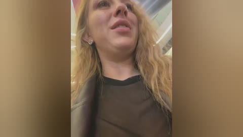 Media: A video of a Caucasian woman with long, wavy, blonde hair, wearing a black top and a black leather jacket, taken from a low angle.