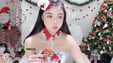 Media: Video of a young East Asian woman with straight black hair, wearing a festive Santa outfit, holding a burger, in a Christmas-themed room with a decorated tree.