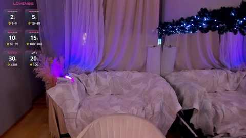 Media: Video of a dimly-lit room with two beds covered in white sheets, purple and blue LED lights, and a Christmas tree in the background.