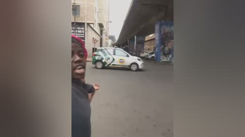 Media: Video of a man in a red cap, wearing a dark shirt, gesturing angrily beside a police van on a busy street under an overpass.