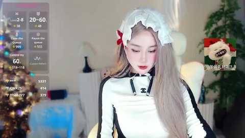 Media: Video of a young Asian woman in a maid outfit, standing in a festive room with a Christmas tree, wearing a white frilled headband and red bow.