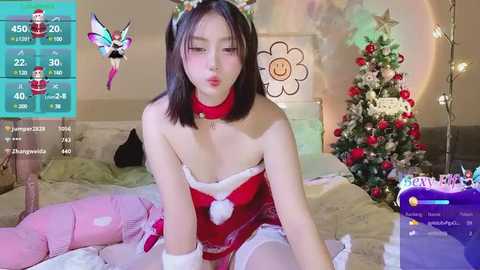 Media: Video of an Asian woman with shoulder-length black hair, wearing a Santa-themed outfit, sitting on a bed. A Christmas tree and decorations are visible in the background.