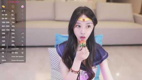 Media: Video of an Asian woman in a Sailor Moon cosplay, holding a red apple, in a modern living room with beige couches and light flooring.