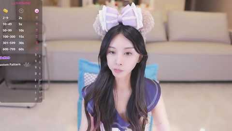 Media: Video of an Asian woman with long black hair, wearing a purple sailor outfit and cat ears, kneeling on a light-colored floor in a modern living room.