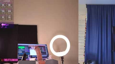 Media: Video of a modern bedroom with a bright, round light ring on a stand, a TV displaying a game, a blue curtain, and a pink logo in the corner.