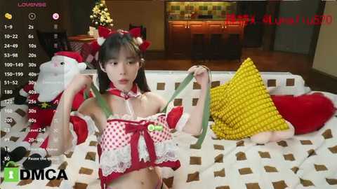 Media: A video of an Asian woman in a festive, revealing Santa outfit, sitting on a bed with Christmas decorations in the background.