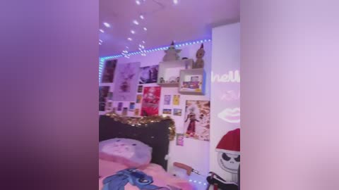 Media: Video of a cozy, pink-themed bedroom with a bed adorned with plush toys, fairy lights, and a string of lights above. Walls are covered with posters and artwork.