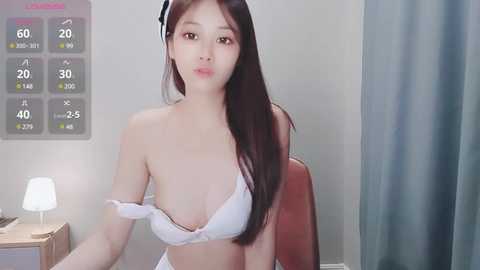 Media: Video of an Asian woman with long black hair, wearing a white bra, sitting at a desk with a monitor displaying temperature data.