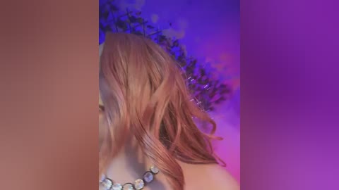 Media: Video of a person with long, wavy, light brown hair, wearing a beaded necklace, set against a purple and blue gradient background. The image is slightly blurred, giving it a dreamy, ethereal feel.