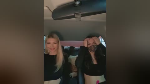 Media: Video of two young women, one with long blonde hair, smiling, the other with brown hair, covering face, seated in a car.