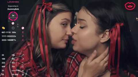 Media: A video captures two young girls, one with dark hair and another with light hair, kissing passionately in a dimly lit room. They wear red plaid shirts, and the image is overlaid with chat icons.